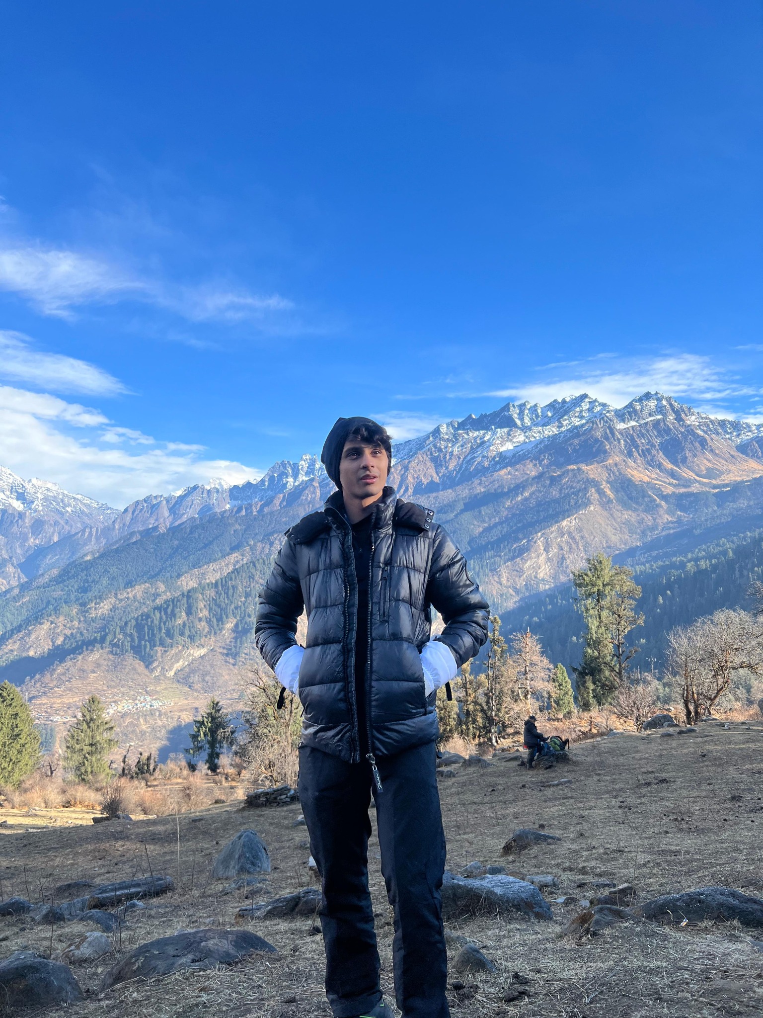 Om Shah outdoors with a mountain landscape behind him
